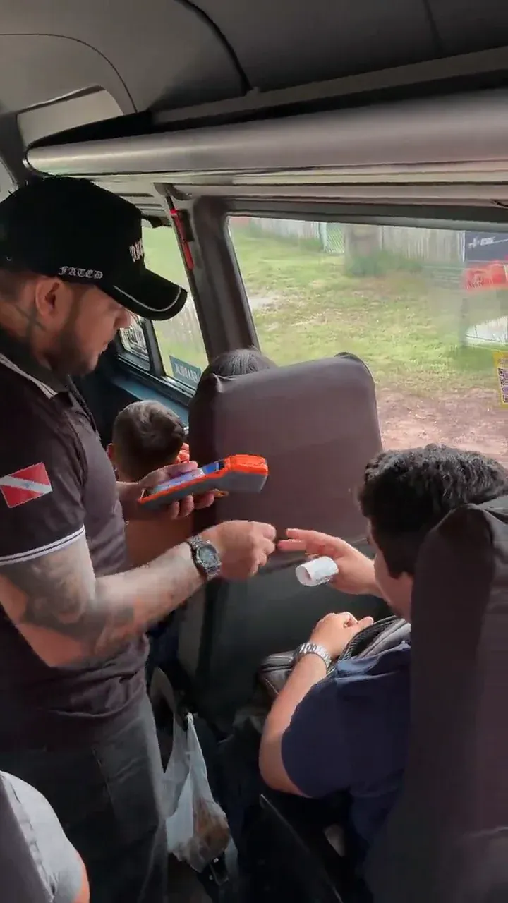 A conductor sells a ticket on board a van, a frame from the NavBus video